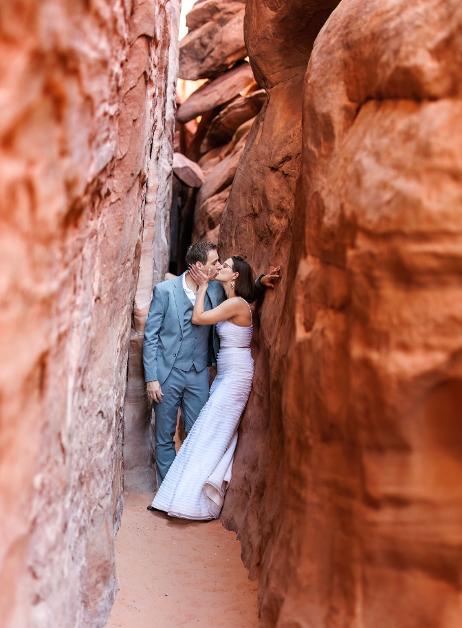 photo of bride and groom kissing between rocks