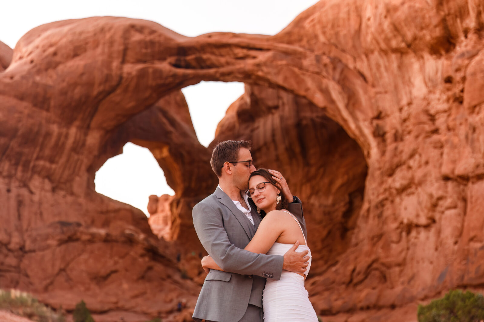 photo of groom kissing bride on her forehead as they embrace