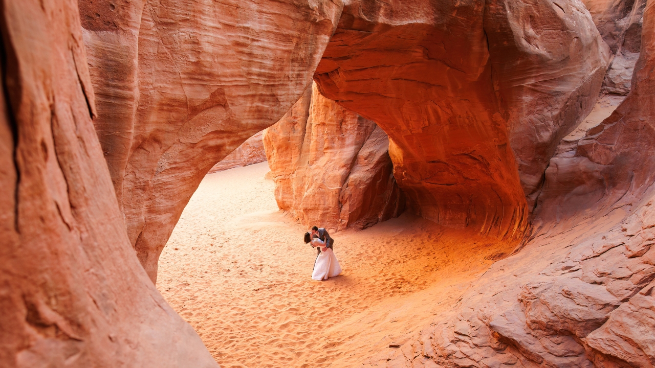 photo of bride and groom kissing under arch with groom dipping her