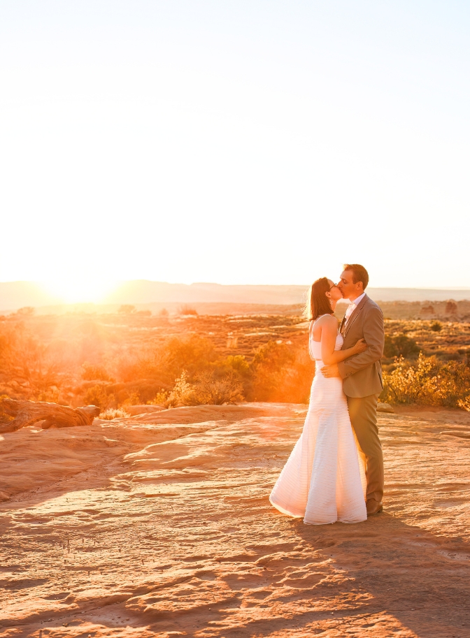 photo of bride and groom kissing with sunsetting behind them