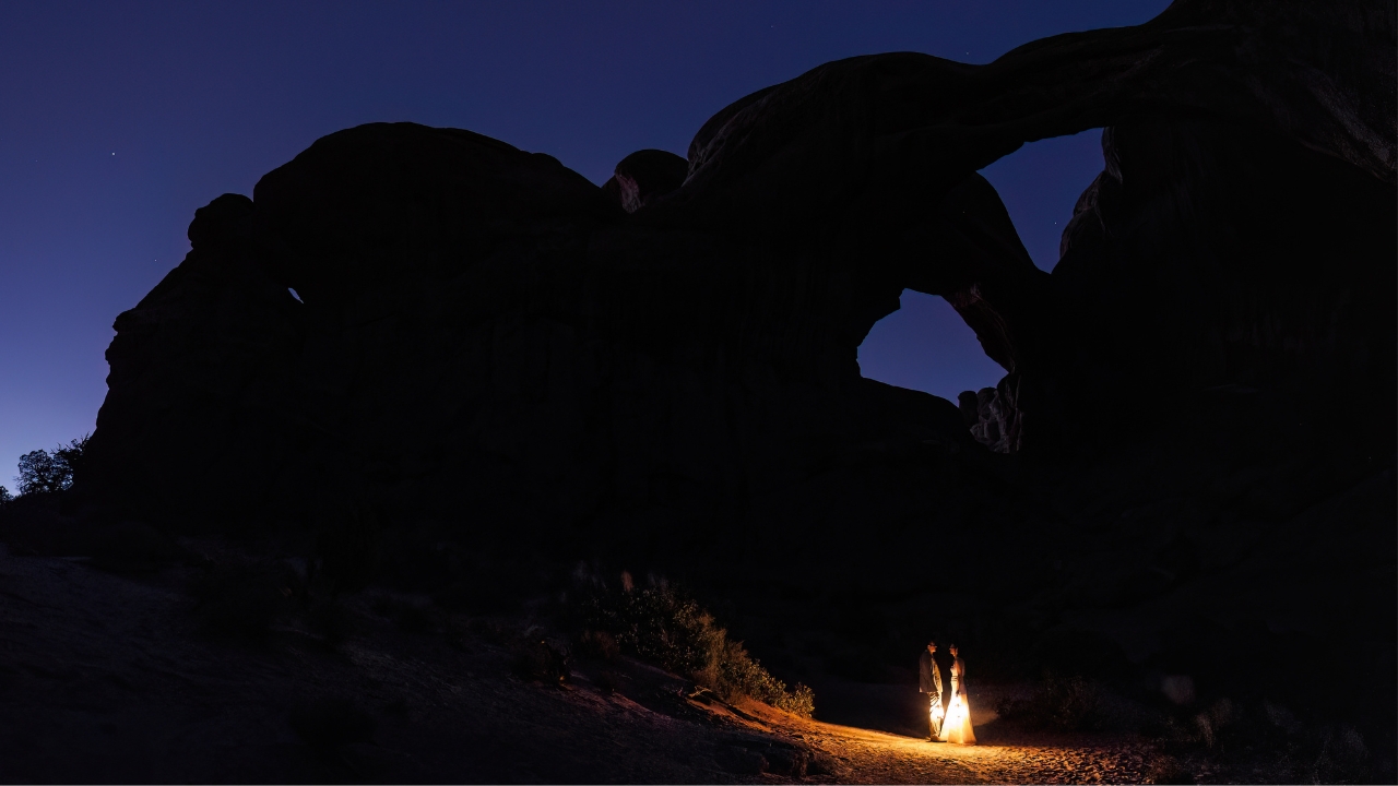 photo of bride and groom holding lanterns in the dark with arches above them in Arches National Park