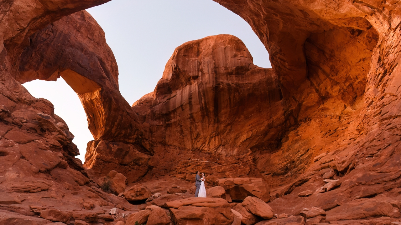 photo of bride and groom holding hands and looking up with the arches at Arches National Park towering over them