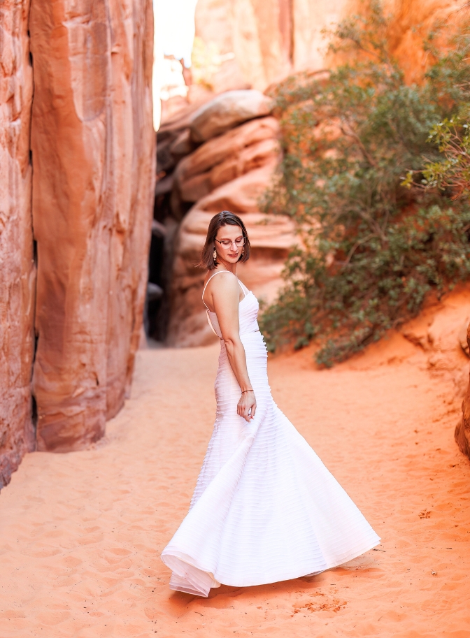 photo of bride swirling in wedding dress with red rocks surrounding her