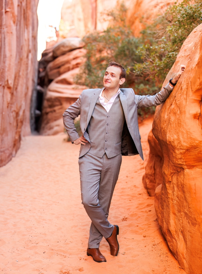 photo of groom leaning on rock and posing 