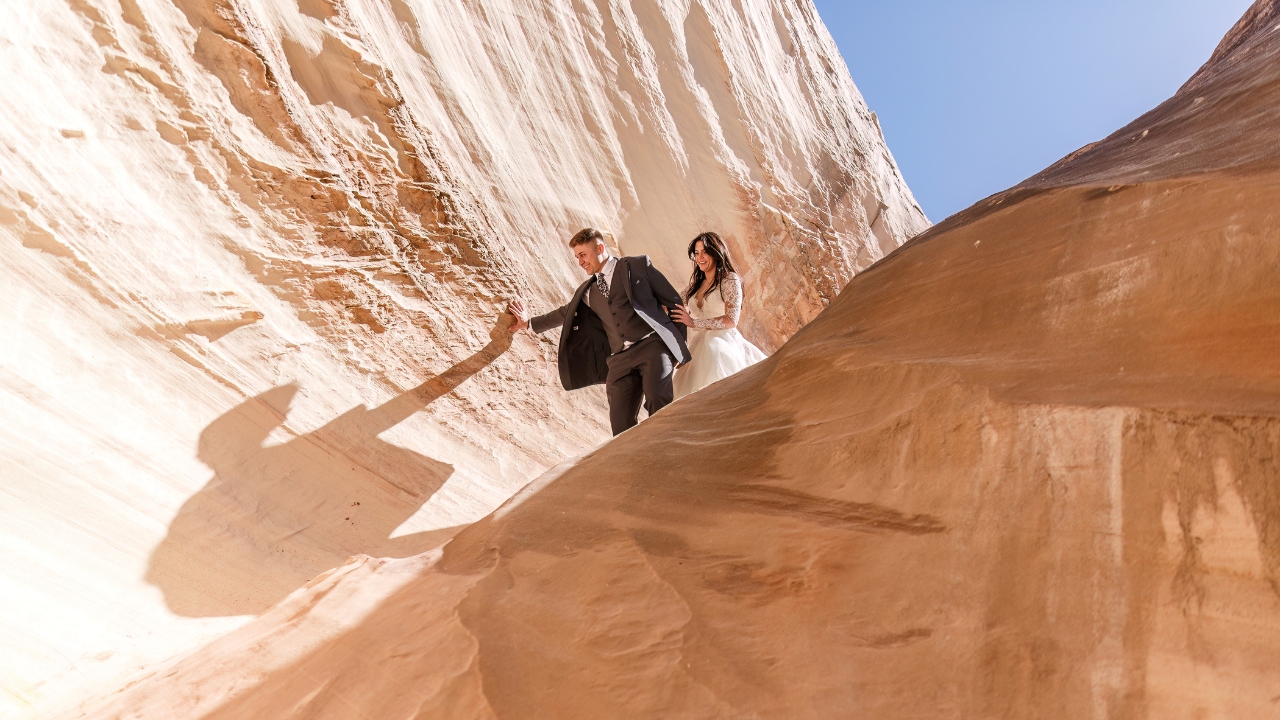 photo of bride and groom hiking down white slot canyon for elopement