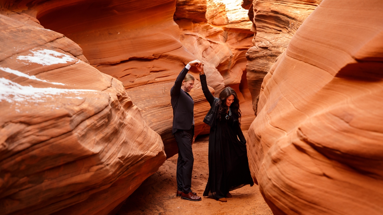 photo of groom twirling bride in between red slot canyon