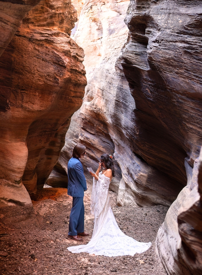 photo of bride crying as she exchanges vows with groom on wedding day in a slot canyon