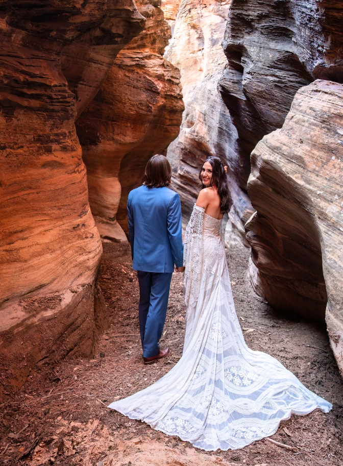 photo of bride and groom walking hand and hand and bride looking back at camera