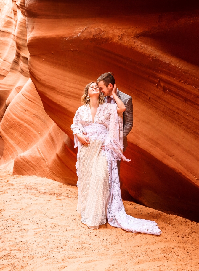 photo of groom holding bride from behind as she laughs and has her hand around his head