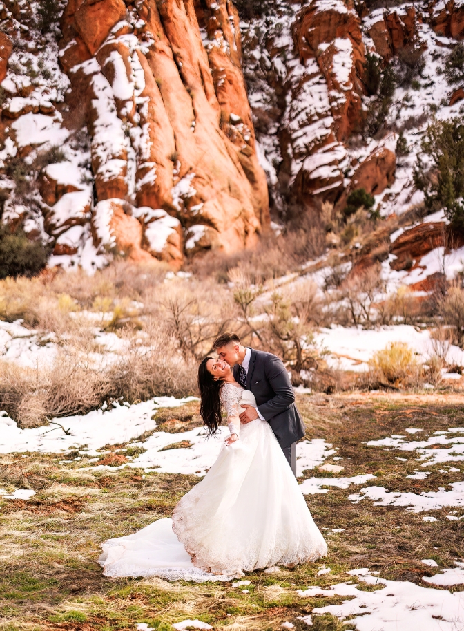 photo of groom kissing bride on the cheek surrounded by snow