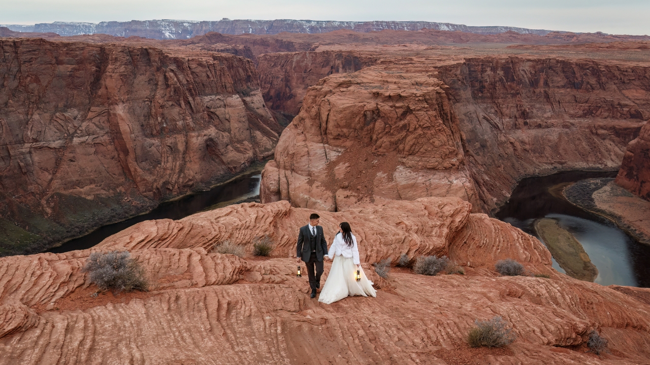 photo of bride and groom holding hands and carrying lanterns on their wedding day at Horseshoe Bend