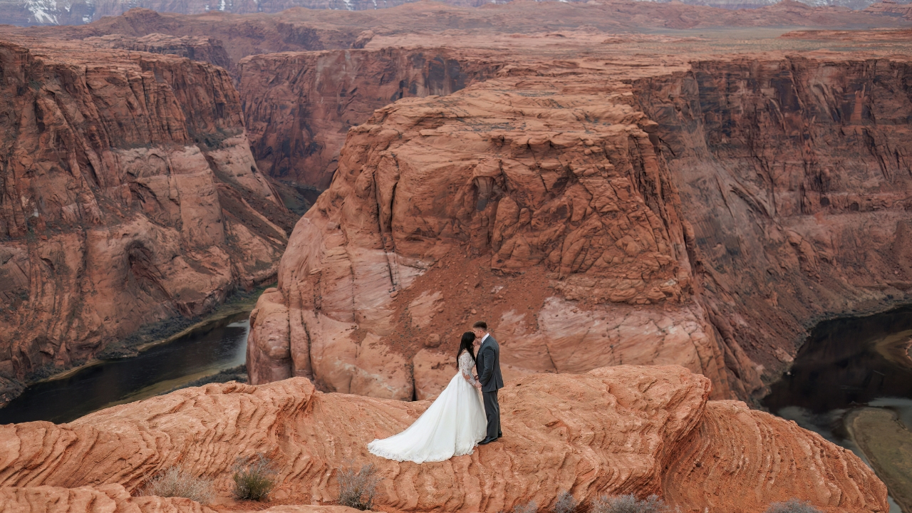 photo of groom kissing bride on the forehead with the Colorado River behind them at Horseshoe Bend