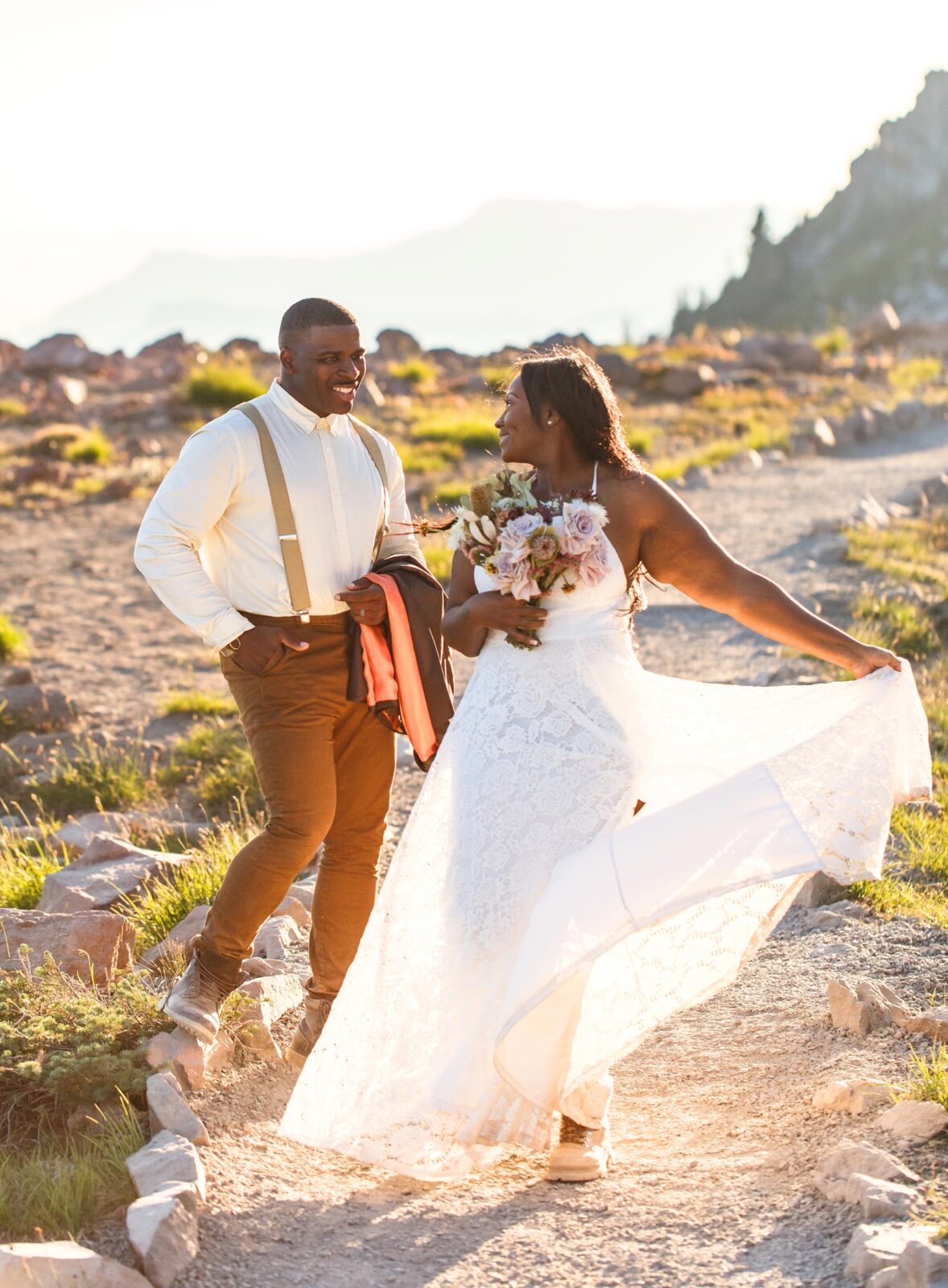 photo of bride looking back at groom and twirling her dress as he smiles as her for their Mt Rainier wedding