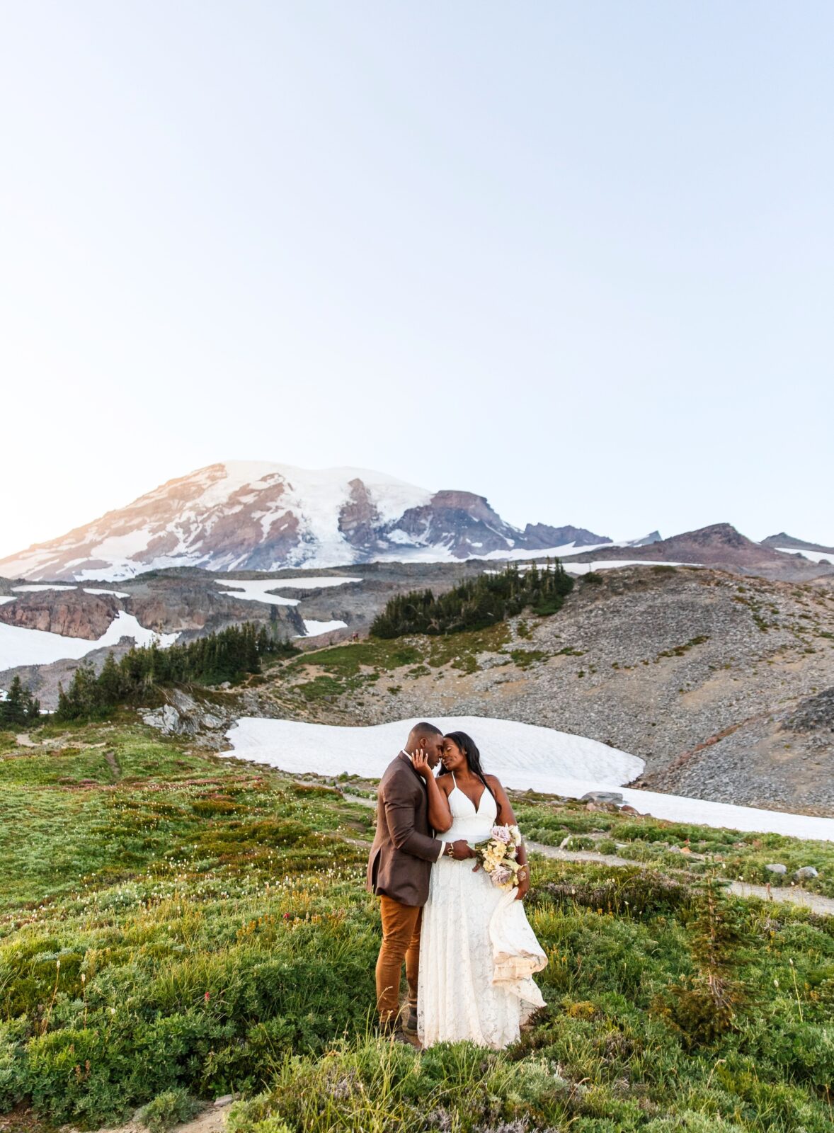 photo of groom hugging bride from behind as she caresses his face and are forehead to forehead in Mt Rainier