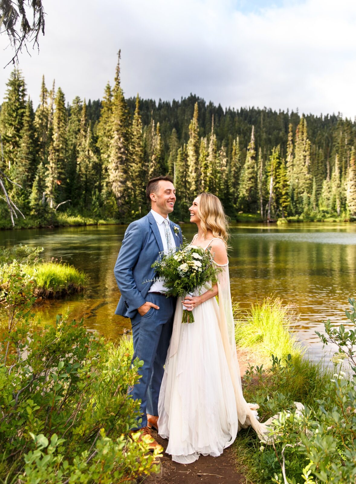 photo of bride and groom laughing with lake and trees behind them on wedding day