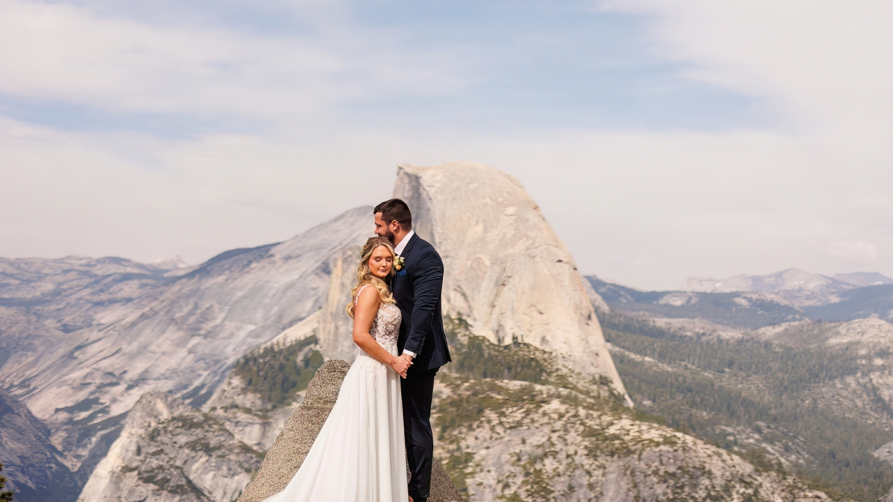 photo of bride and groom embracing with Half Dome behind them