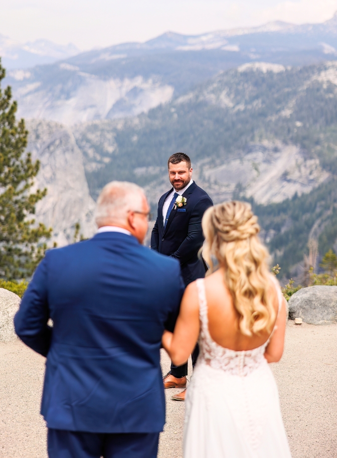 photo of groom watching as father of the bride and bride walk towards him on wedding day