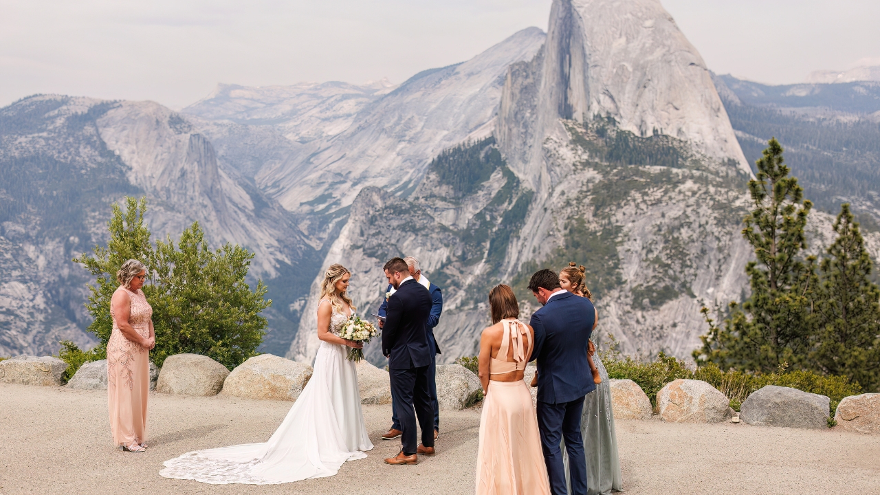 photo of bride and groom surrounded by family with Half Dome in the distance for their Yosemite elopement