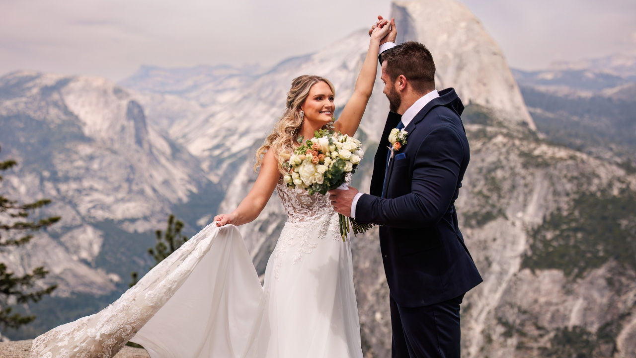 photo of groom spinning bride around at their Yosemite National Park elopement with Half Dome behind them