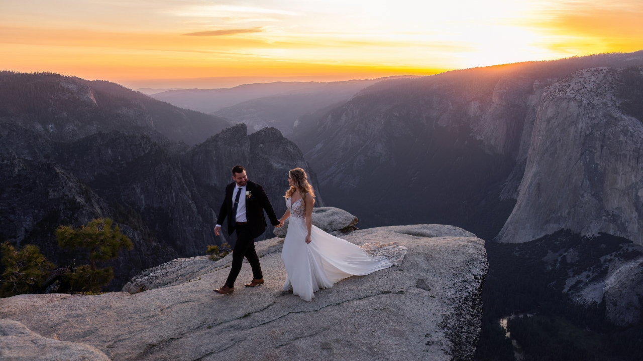 photo of bride and groom holding hands and walking along Taft Point for their Yosemite Elopement