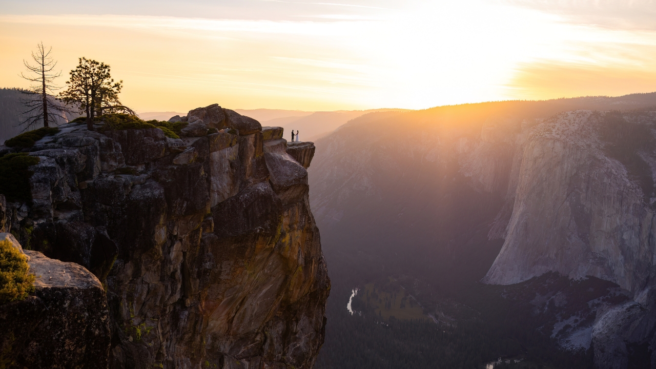 photo of bride and groom in the distance on a cliff at Yosemite National Park at sunsest