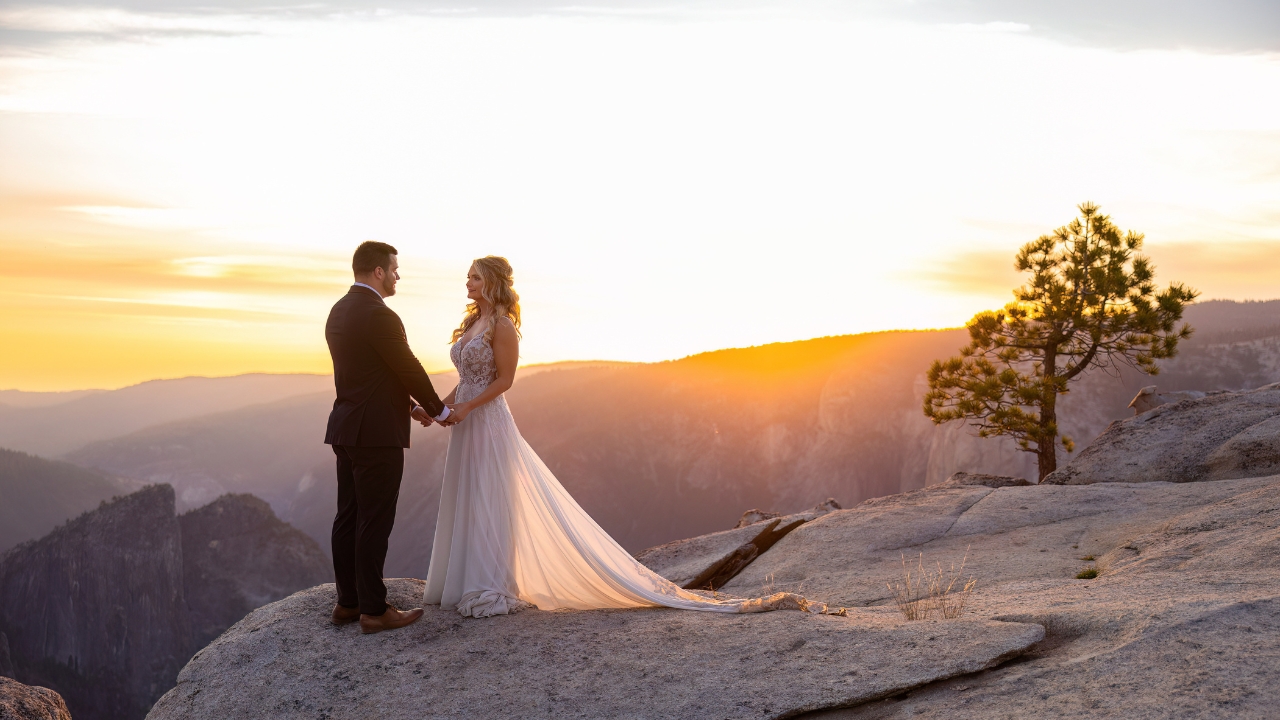 photo of bride and groom facing each other, holding hands and smiling with sunset in the background for Yosemite elopement