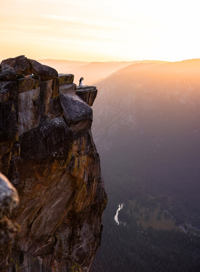 photo of bride and groom far away in the distance on a ledge in Yosemite with the sunsetting behind them