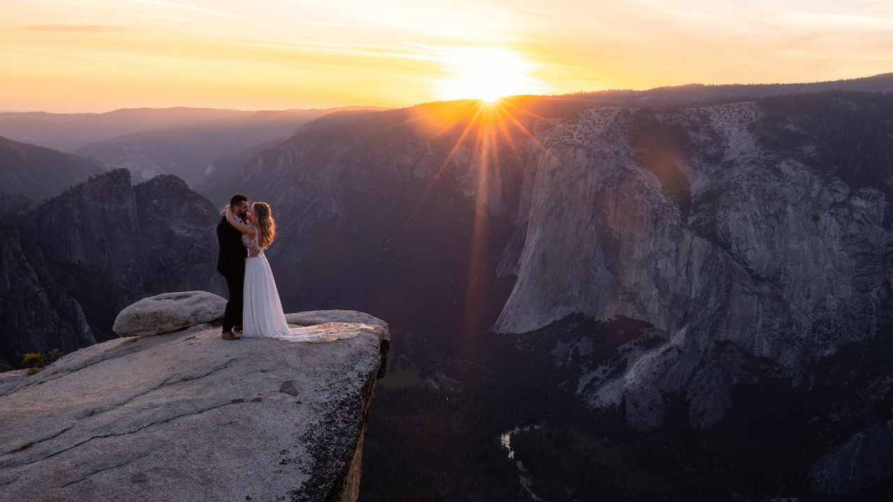 photo of bride and groom holding each other and staring into each others eyes on a ledge above Yosemite Valley