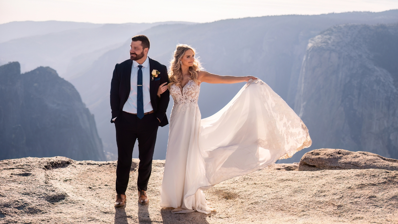 photo of bride and groom linked arm in arm while she holds her train and they look off in the distance