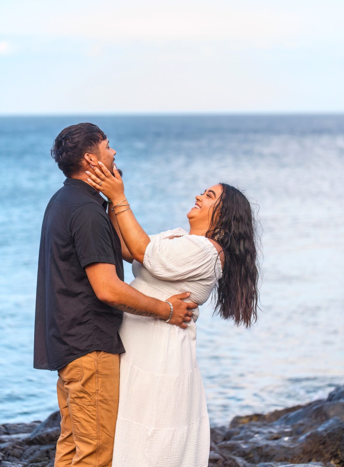 photo of woman holding man's face and laughing as he embraces her