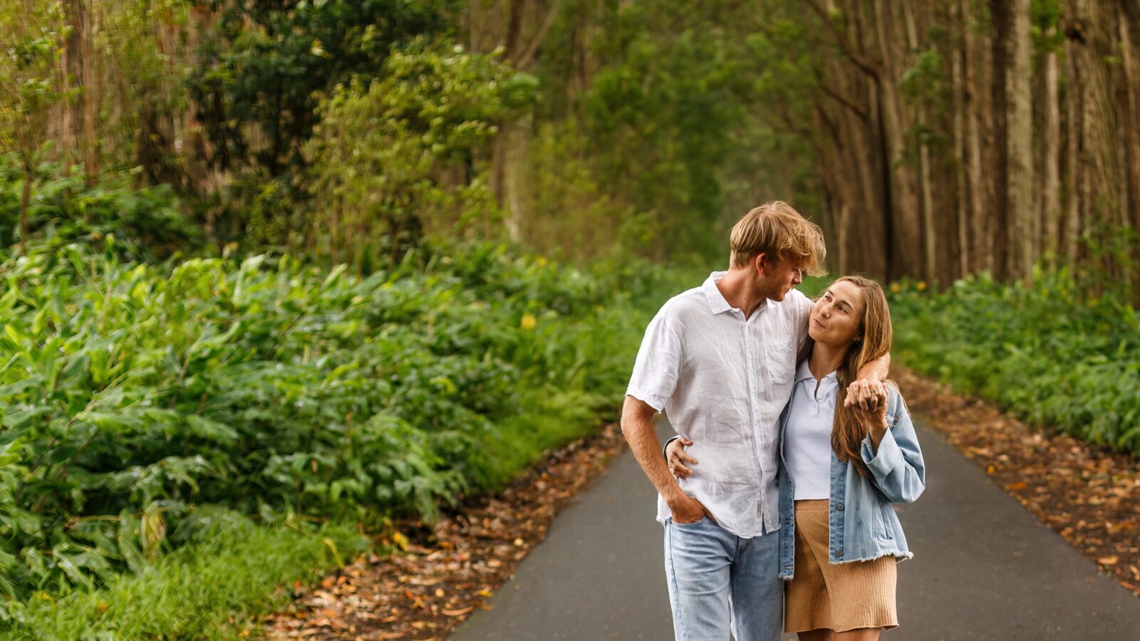 photo of couple walking down the street in Hawaii with their arms wrapped around each other as they stare into each other's eyes