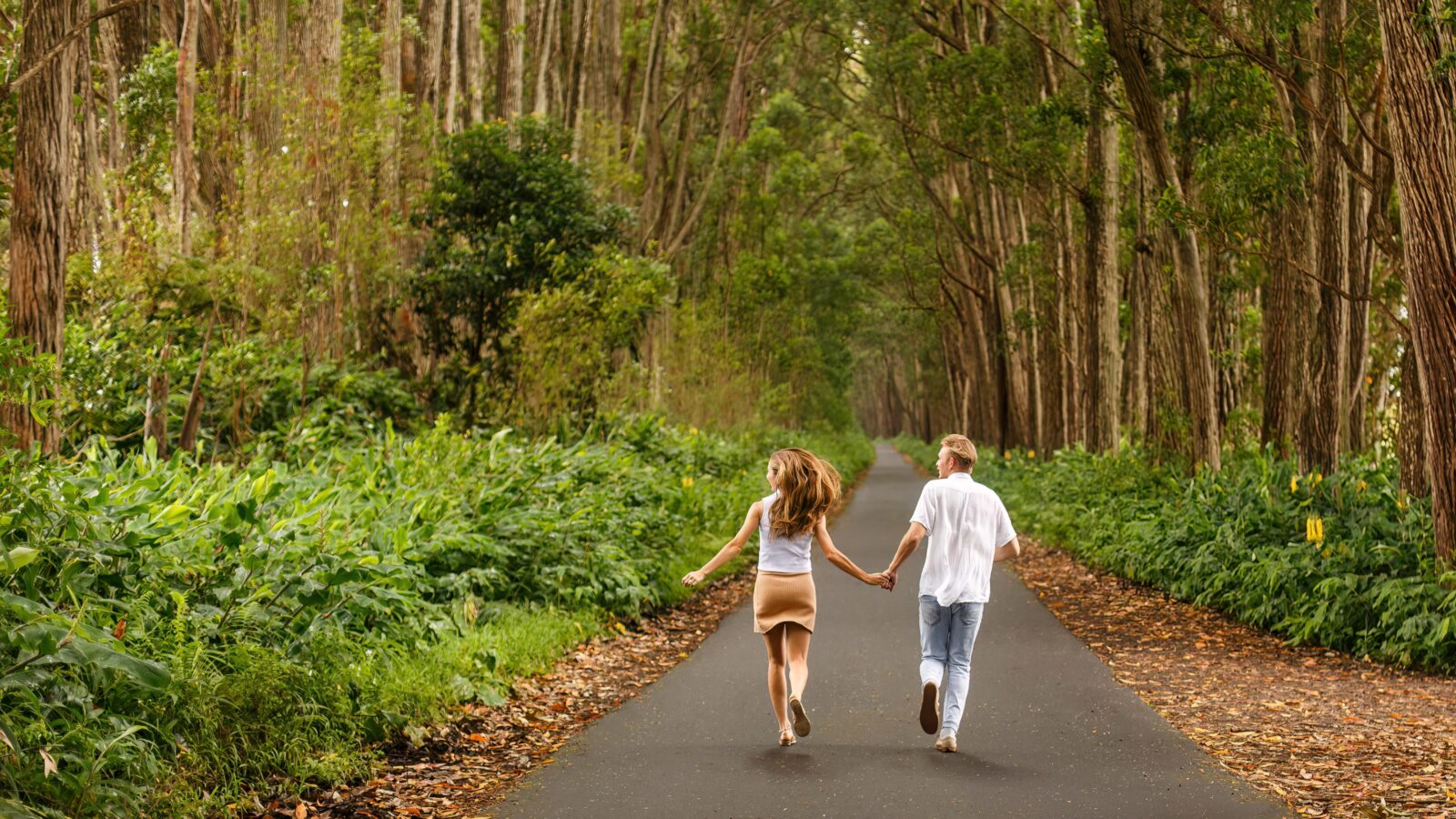 photo of couple holding hands and running down the road in Hawaii for engagement shoot