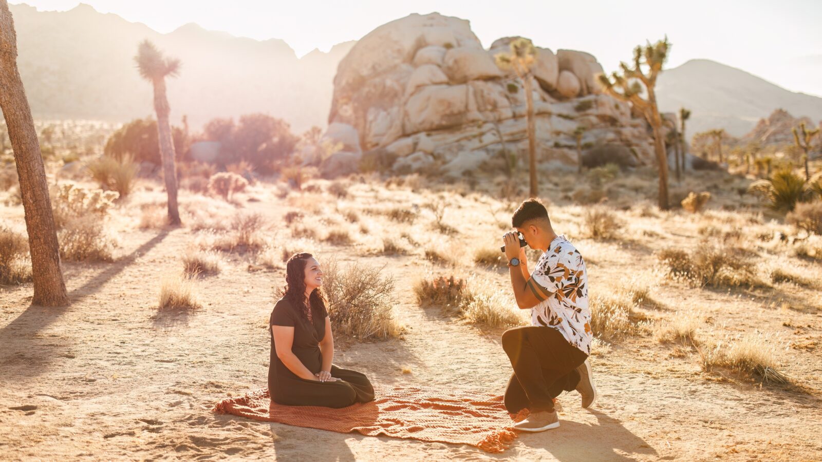 photo of guy taking picture of his fiancée in the middle of a desert