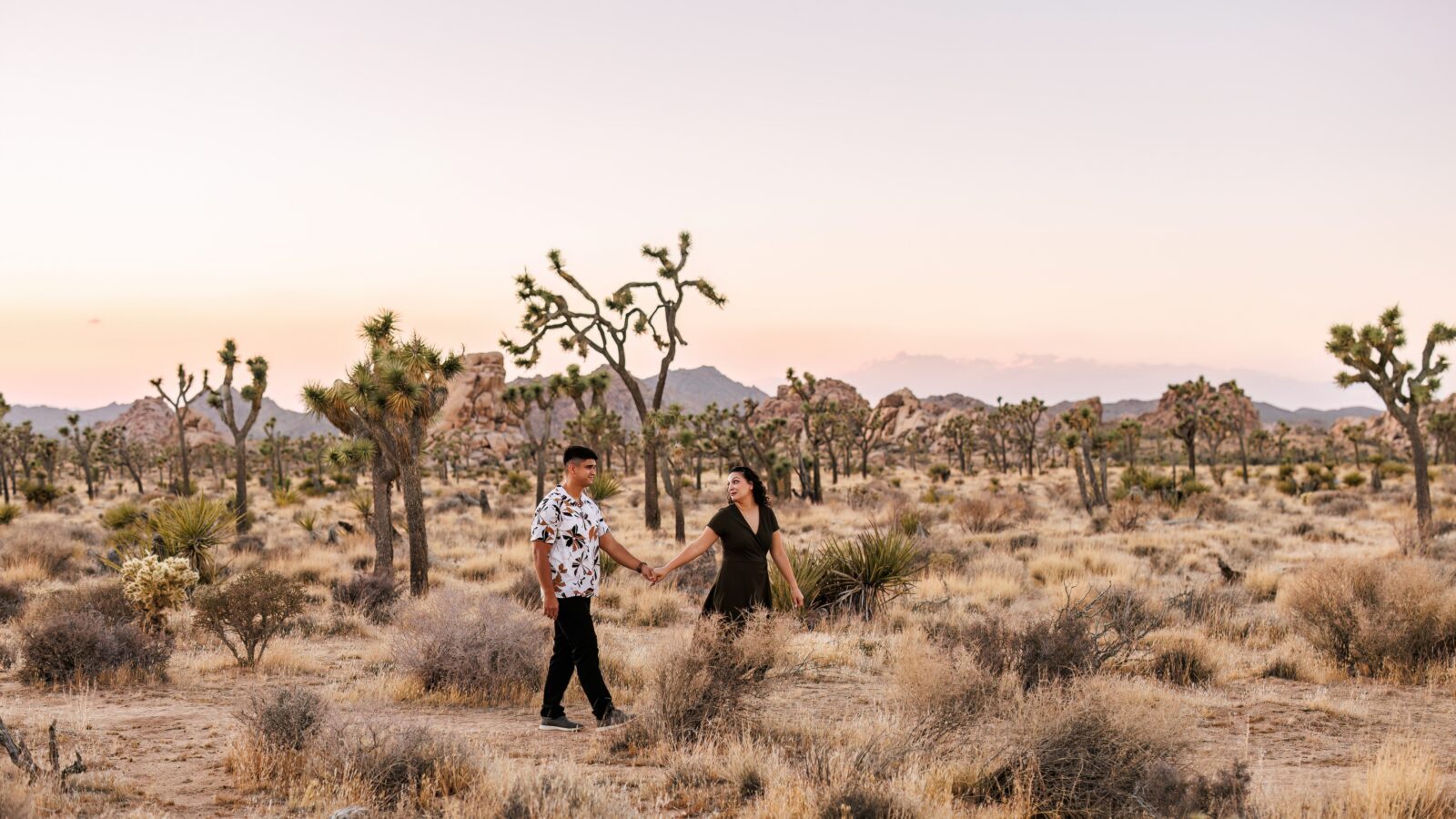 photo of couple holding hands and walking through the desert at Joshua Tree for engagement photoshoot