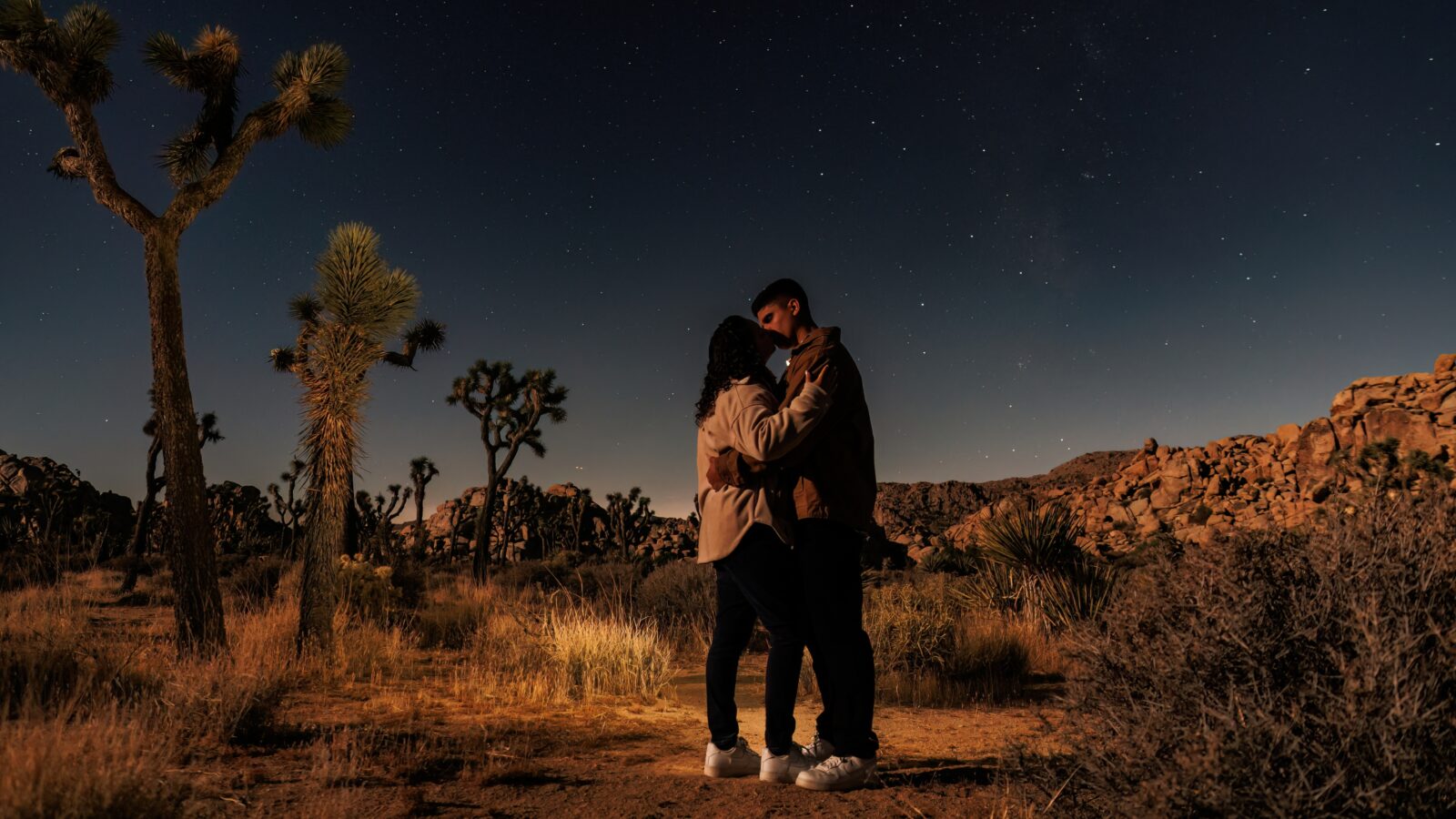 photo of couple holding each other and kissing with stars lit up behind them