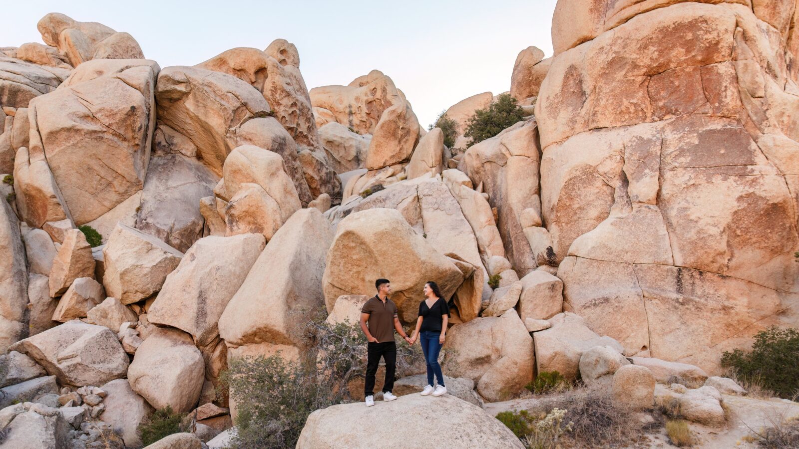 photo of couple holding hands and looking at each other while surrounded by large rocks at Joshua Tree National Park