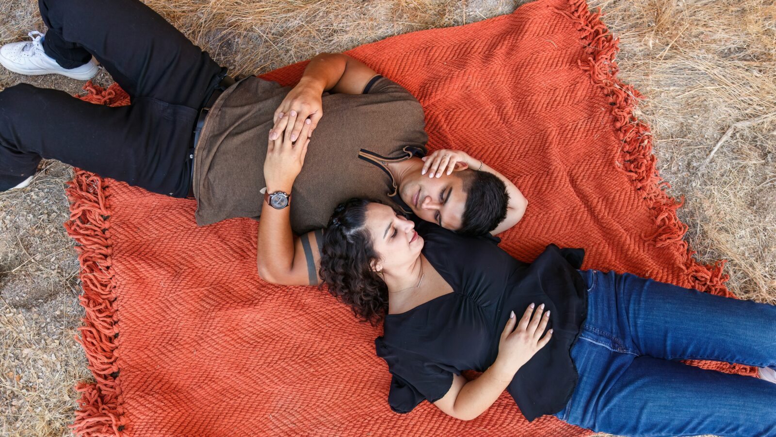 photo of couple laying down on blanket and staring into each other's eyes