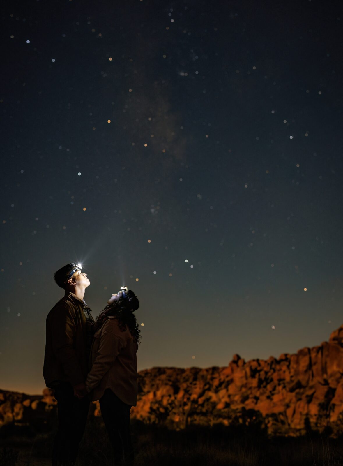 photo of couple looking up at night sky and being surrounded by stars at Joshua Tree 