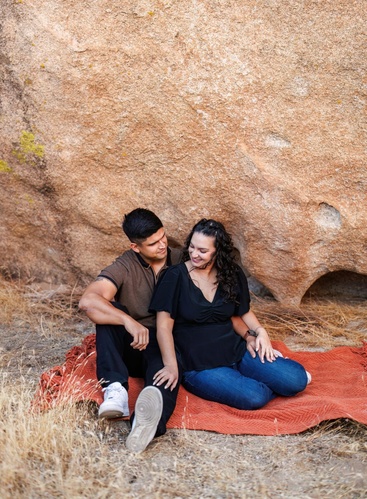 photo of woman holding fiancée's leg as they have a picnic for their Joshua Tree engagement photoshoot