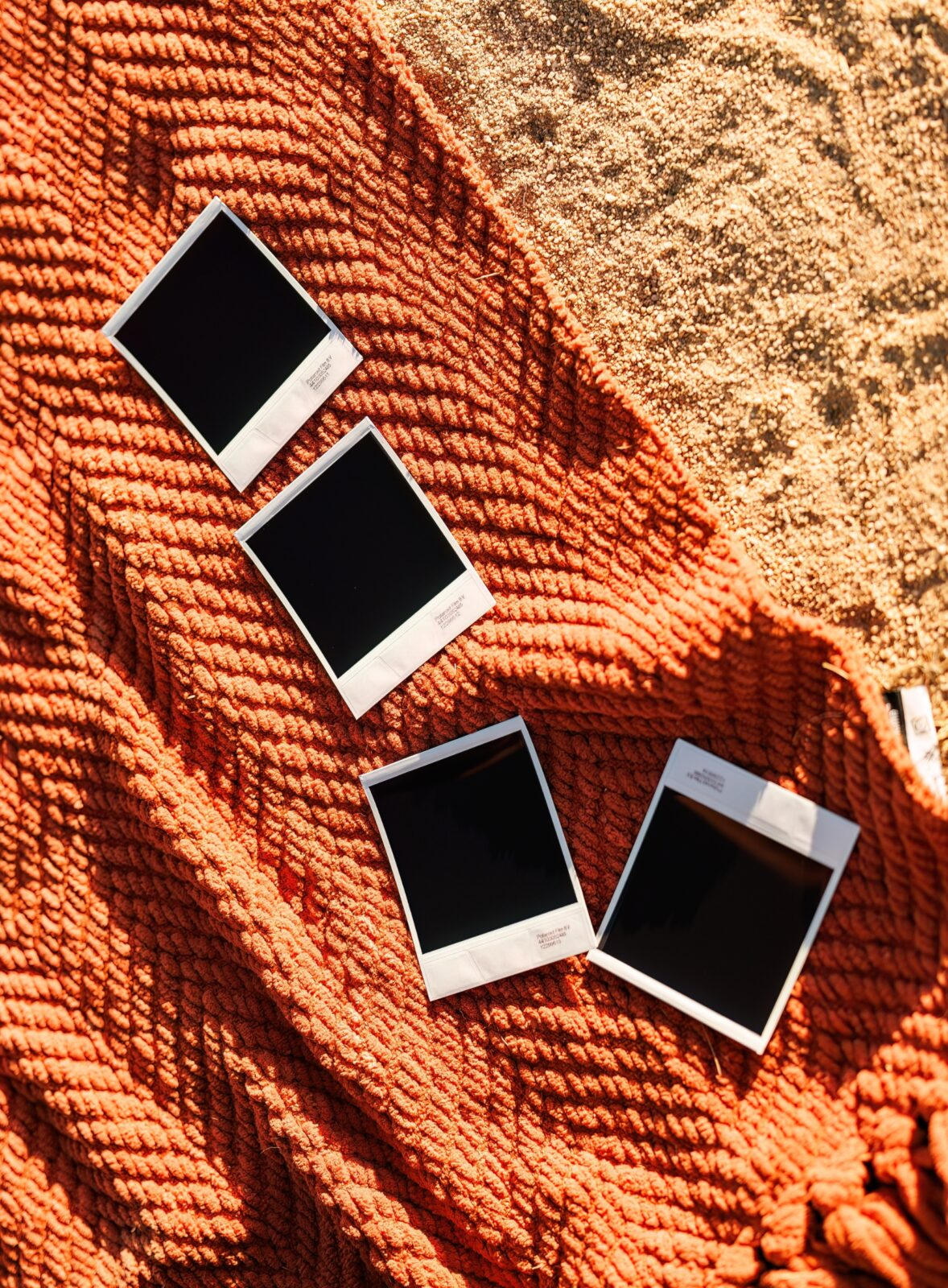 photo of polaroid photos developing on orange blanket