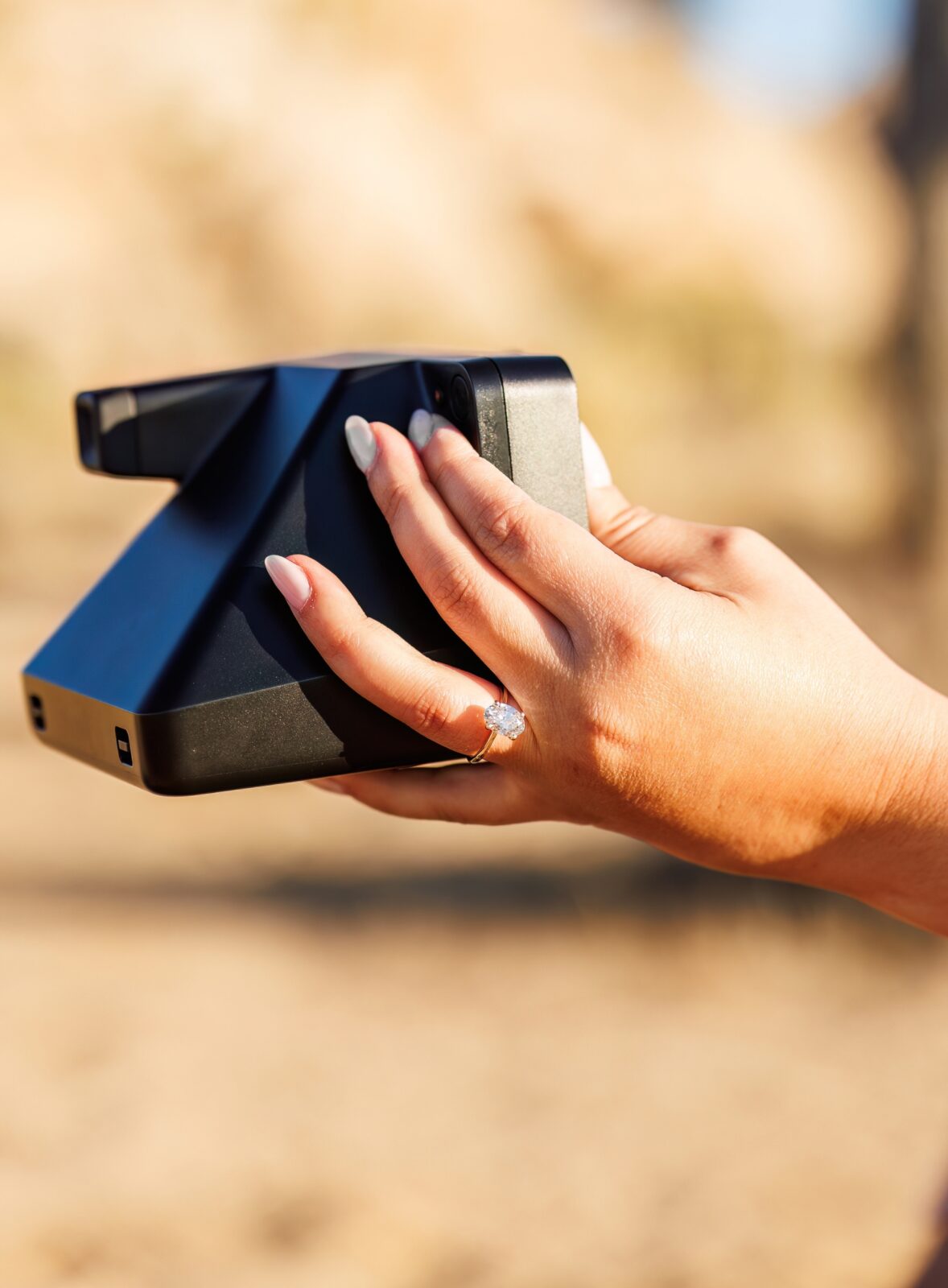 photo of woman's hand holding a polaroid camera