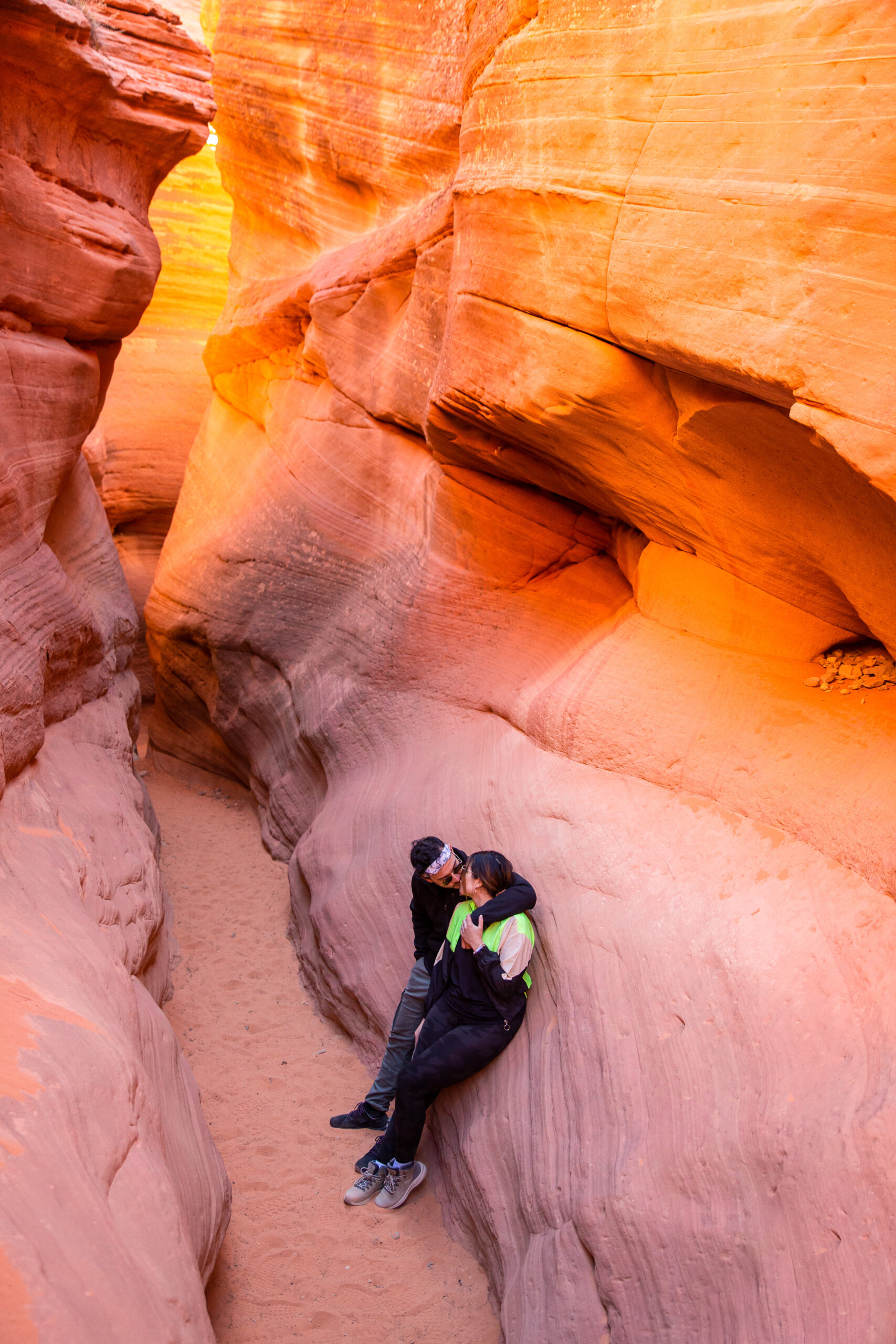 newly engaged couple leaning against the rocks in the canyon kissing each other after their proposal