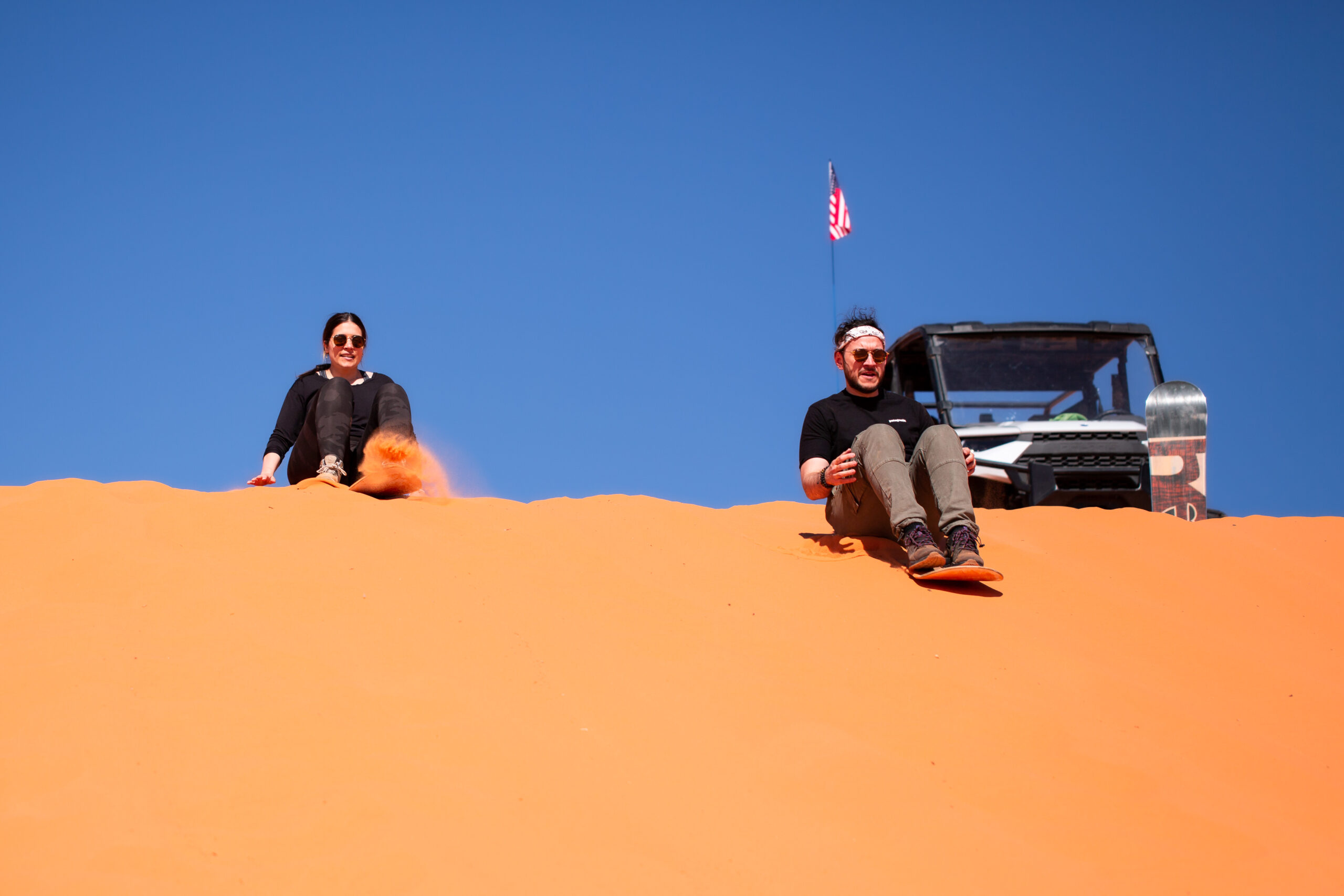 a couple sand boarding down a sand dune after the man proposed 