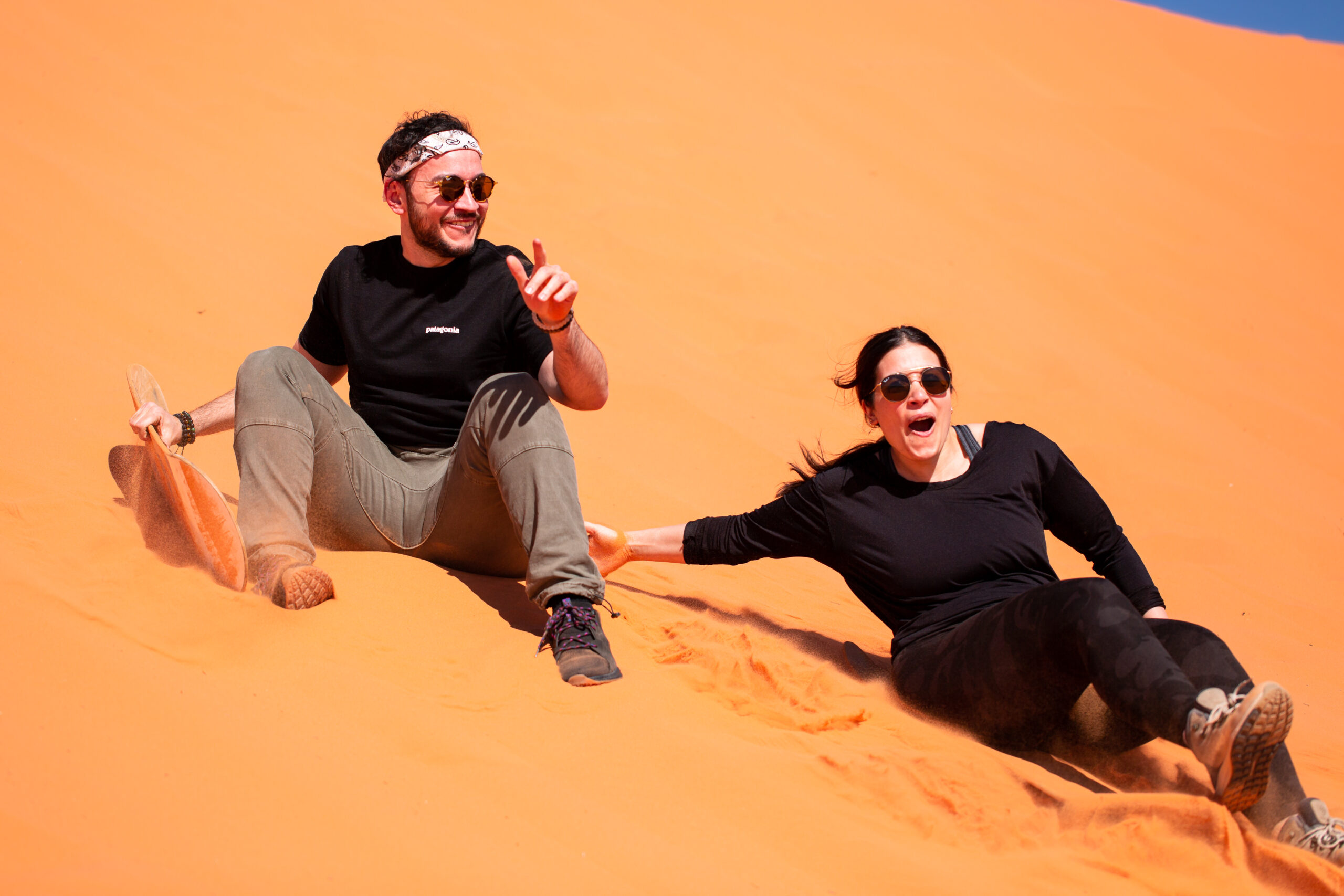 candid moment of a couple sand boarding in Utah 