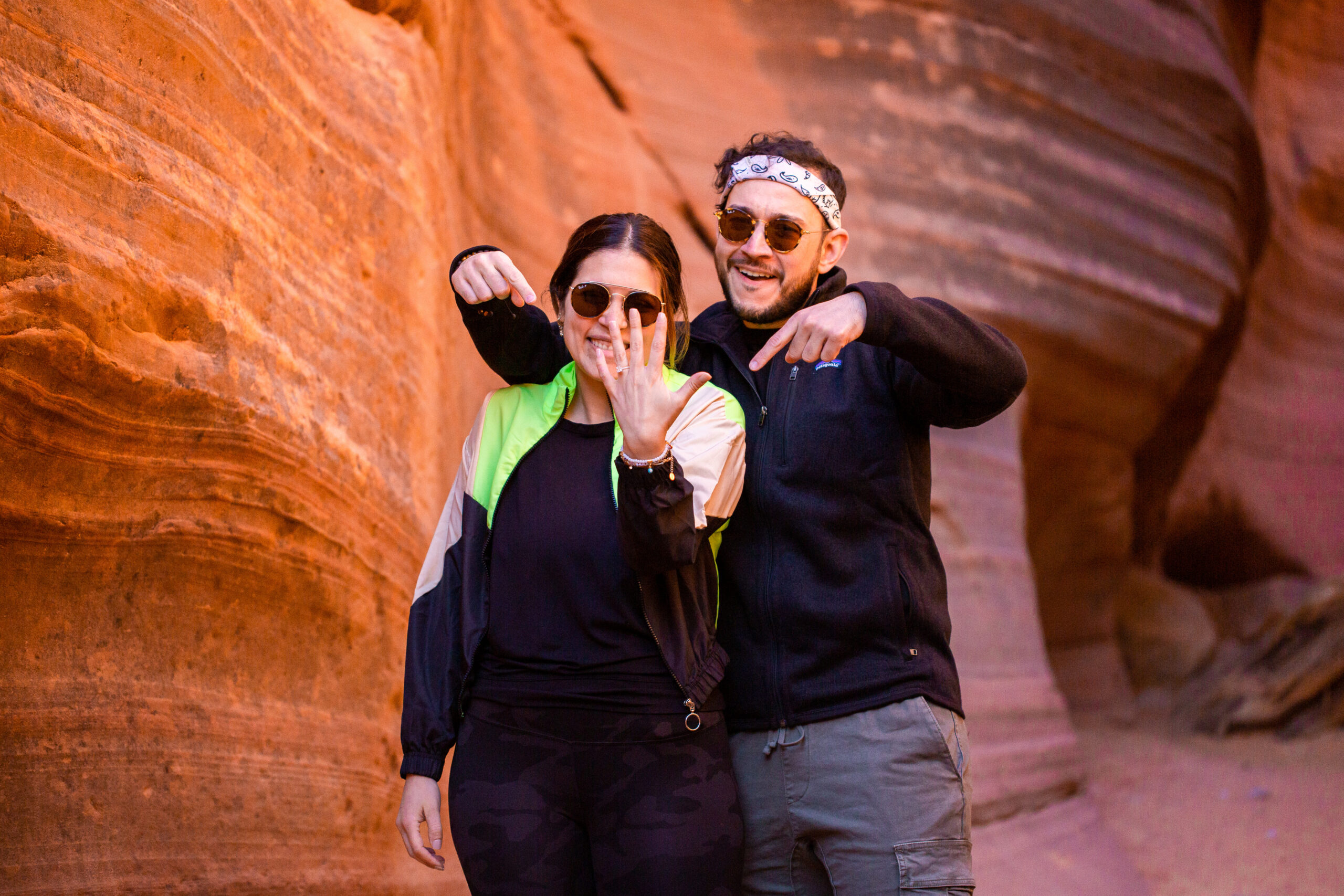 the newly engaged couple showing off the ring and smiling in the canyons 