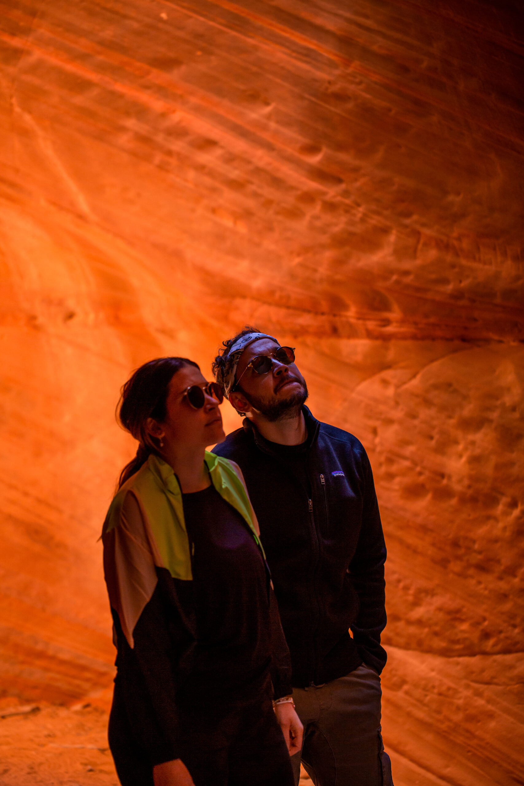 a couple in the shadows of the canyon looking up at the rock formations 