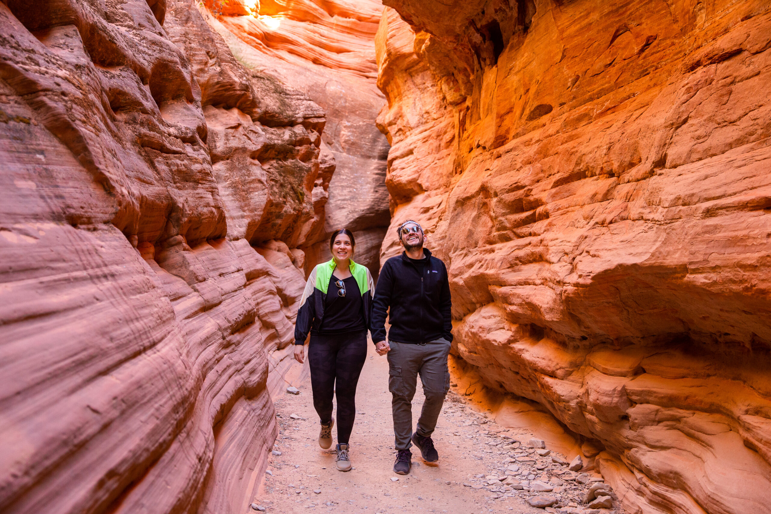 a couple walking through the red rocks and holding hands after their marriage proposal 