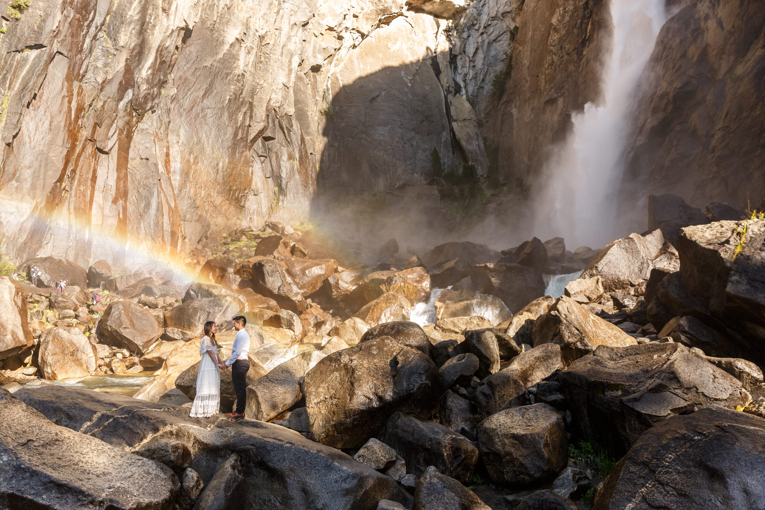 married couple standing by a powerful waterfall in Yosemite during their After Wedding Photoshoot