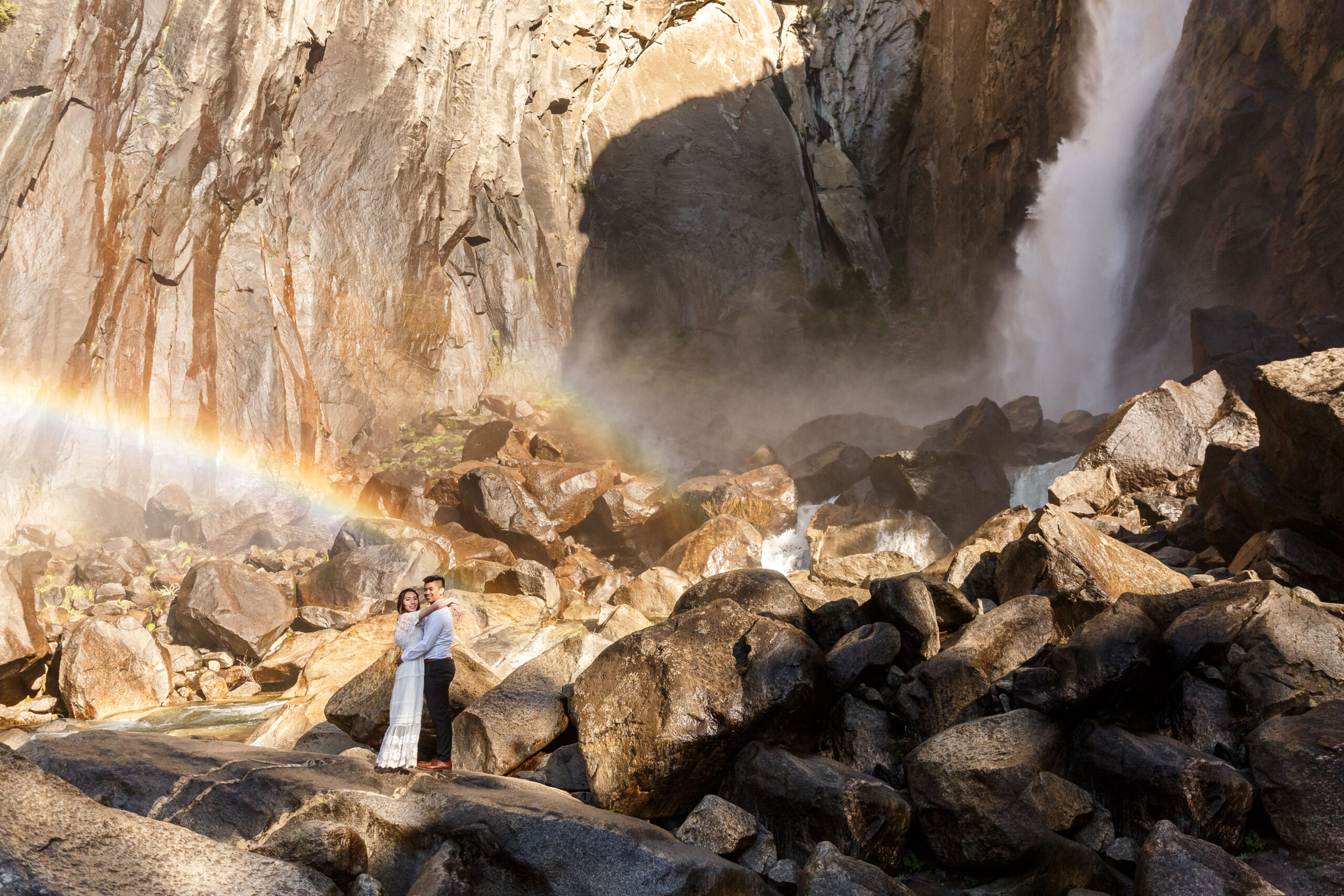 a couple standing next to a powerful waterfall during their After Wedding Photoshoot