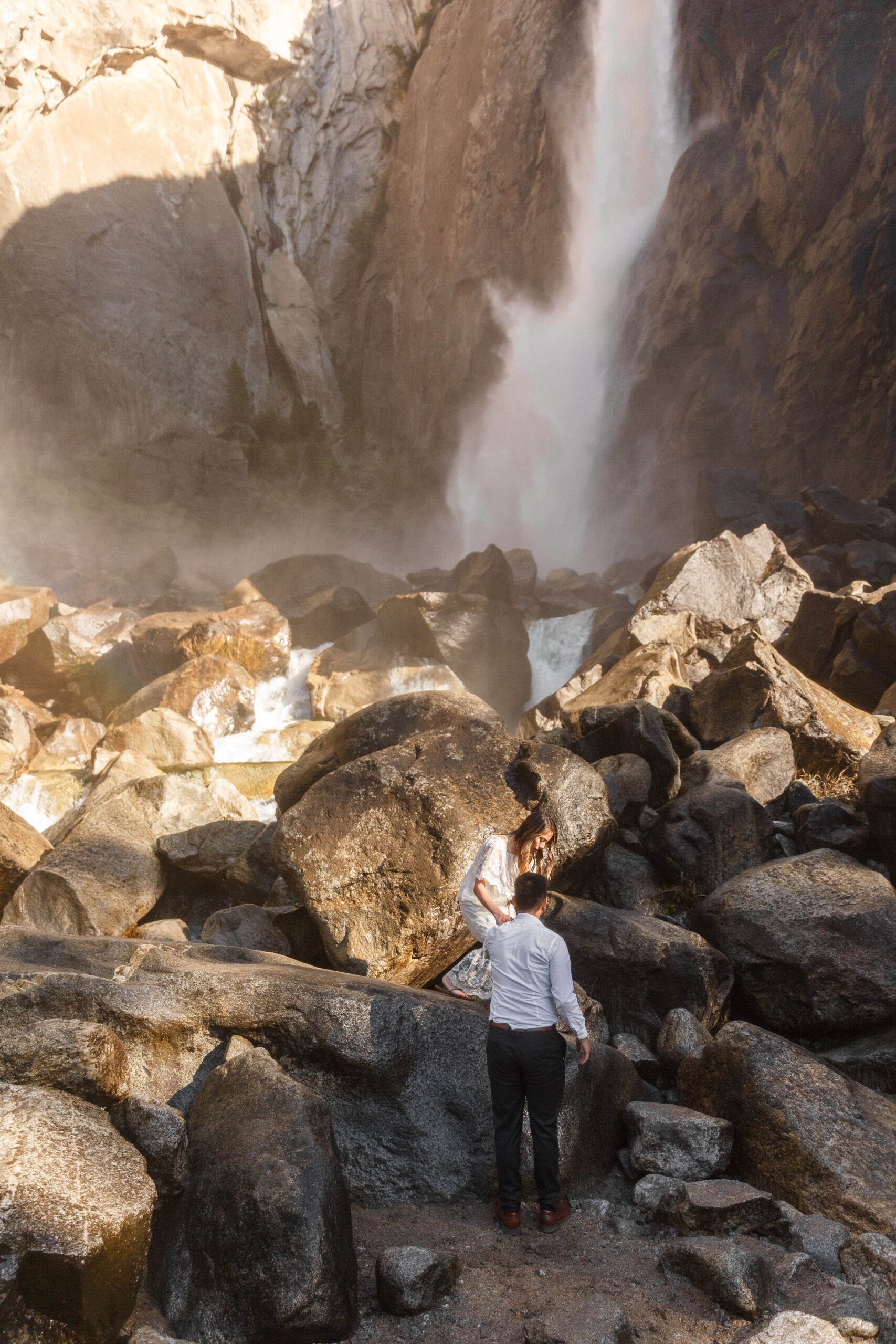 a couple walking through rocks to get down from the waterfall during an After Wedding Photoshoot